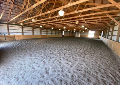 An expansive arena with a sandy floor and sturdy wooden beams.