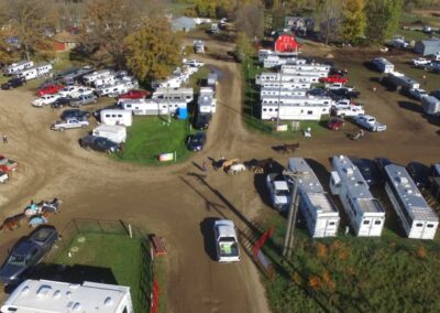 An aerial view of an RV park with horses and trailers situated near an arena.