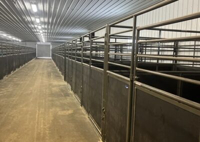 The inside of a barn arena with many stalls.
