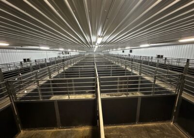 The inside of a barn arena with a lot of stalls.